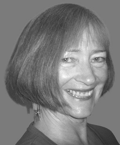 Kvinne med kort rødlig hår smiler mot kamera